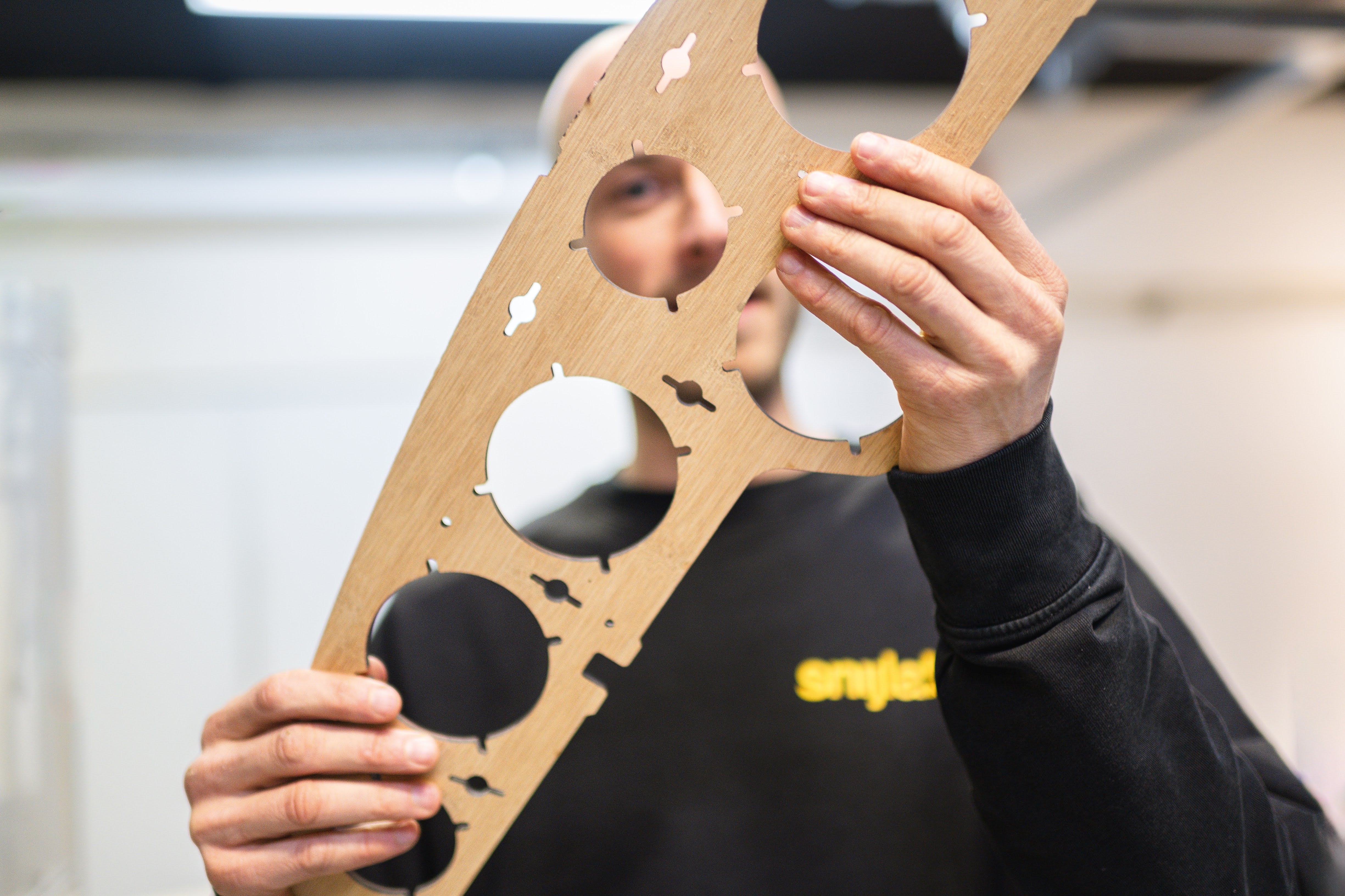 Employee holding a bamboo laser cut instrument panel